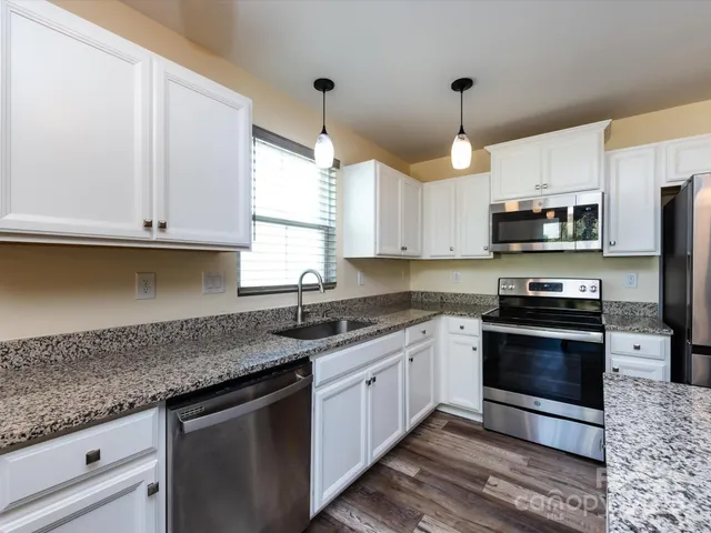 a kitchen with stainless steel appliances granite countertop a sink a stove and a microwave