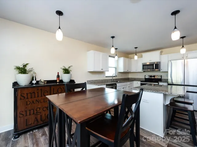 a kitchen with stainless steel appliances a table chairs refrigerator and microwave