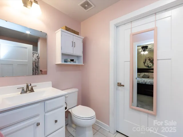 a room with a bed a mirror on dresser and a window