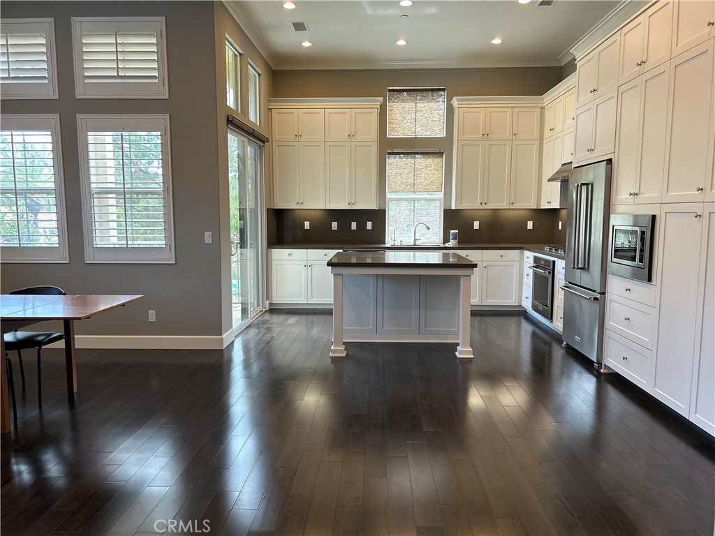 134 Rodeo Irvine, CA 92602 - Photo 7 of 23 a kitchen with stainless steel appliances granite countertop a stove a refrigerator a sink a dining table and chairs with wooden floor