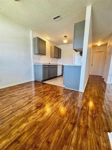 a view of a kitchen with kitchen island wooden floor and stainless steel appliances