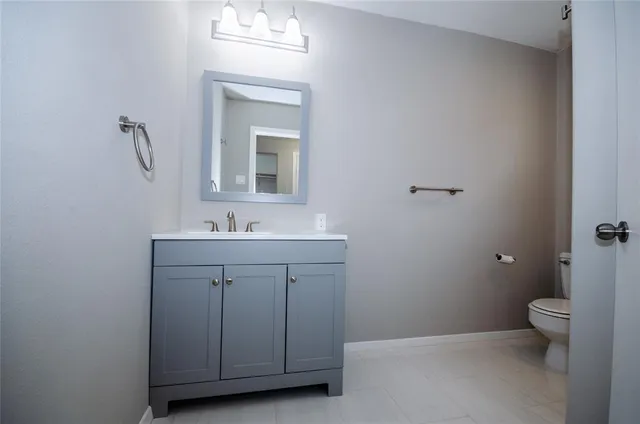 a bathroom with a toilet a sink a mirror and a window