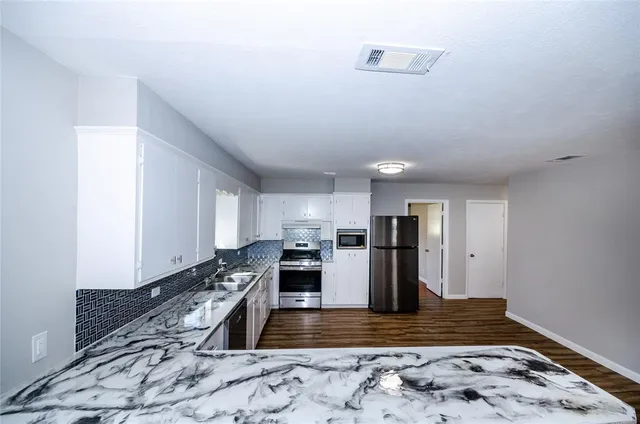 a kitchen with granite countertop a stove a sink dishwasher and a refrigerator
