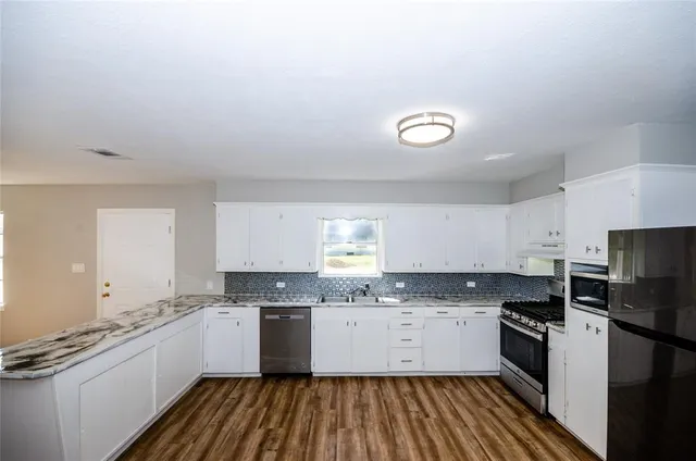 a large kitchen with a lot of counter space and a wooden floor