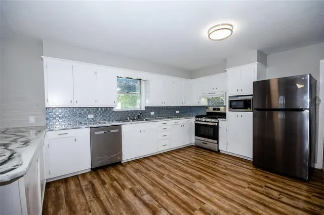 a kitchen with granite countertop stainless steel appliances a refrigerator and a sink