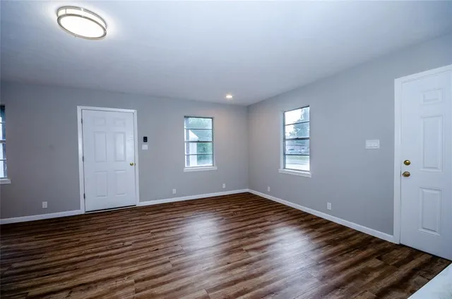 an empty room with wooden floor cabinet and windows