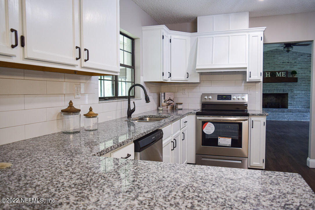 54608 Armstrong Road Callahan, FL 32011 - Photo 8 of 22 a kitchen with stainless steel appliances granite countertop a sink stove and cabinets