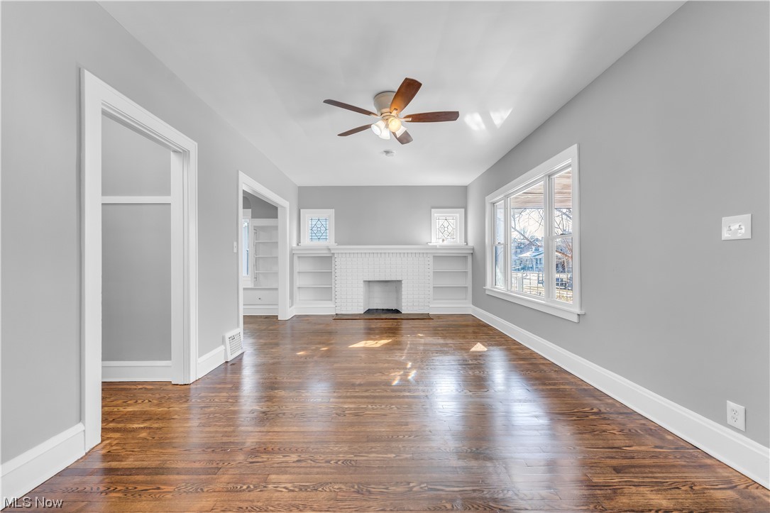 3557 Ludgate Road Cleveland, OH 44120 - Photo 7 of 32 Unfurnished living room with dark wood-type flooring, a fireplace, ceiling fan, and built in shelves