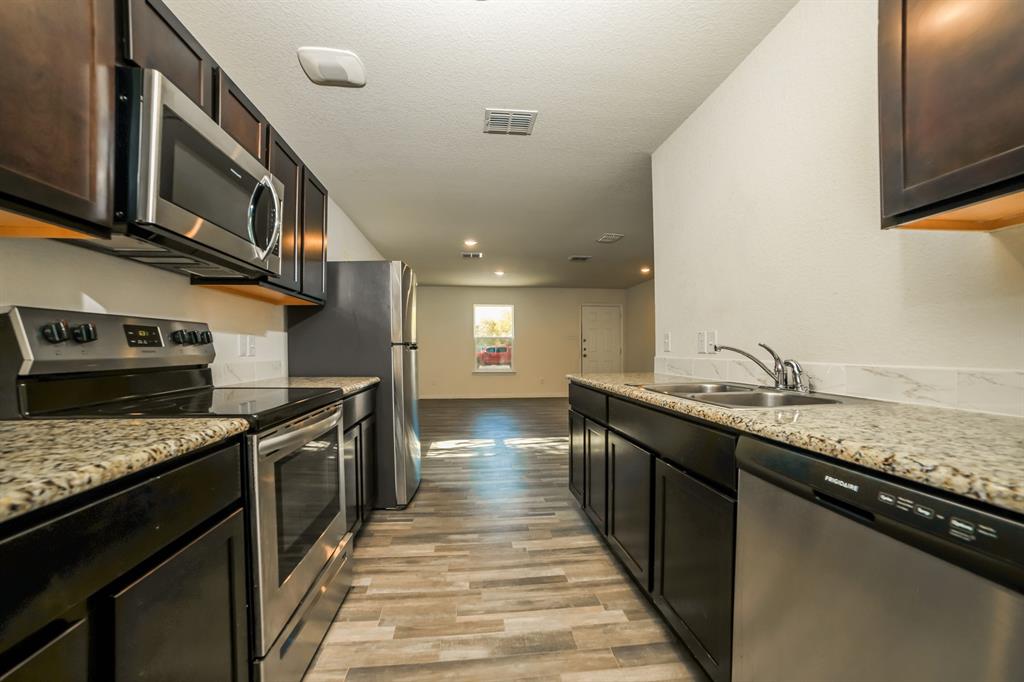 903 Olive Street Waco, TX 76704 - Photo 6 of 21 a kitchen with stainless steel appliances granite countertop a stove a sink and a microwave