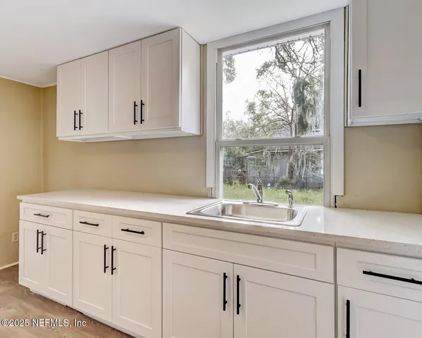 a kitchen with granite countertop white cabinets and a window