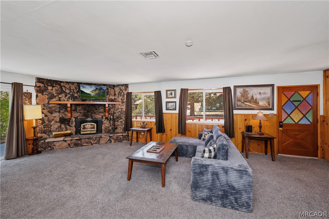 1099 Canyon Road Fawnskin, CA 92333 - Photo 8 of 39 a living room with furniture a flat screen tv and a floor to ceiling window