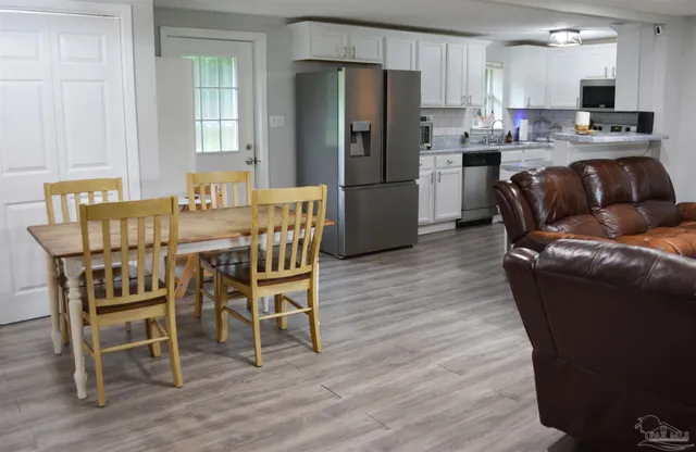 a kitchen with stainless steel appliances kitchen island granite countertop a refrigerator a stove a microwave oven with a dining table and chairs