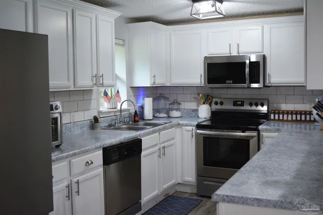 a kitchen with stainless steel appliances granite countertop a sink stove and microwave