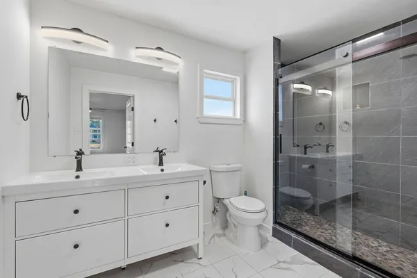 a bathroom with a double vanity sink toilet and shower