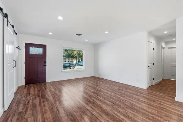 a view of an empty room with wooden floor and a window