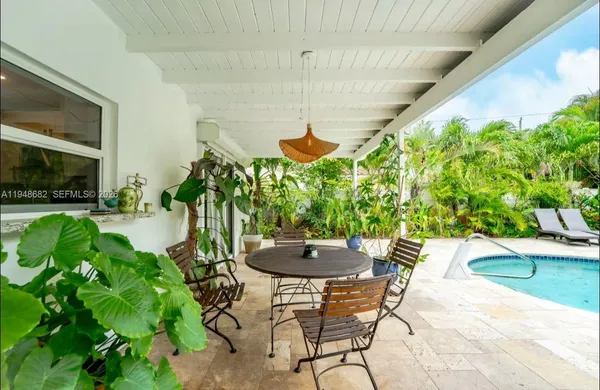 a patio with a table and chairs potted plants