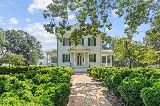 a front view of a house with a yard and fountain in middle