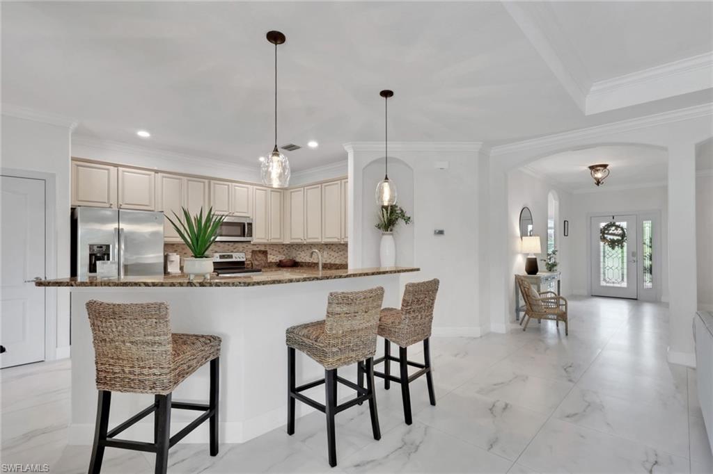 2045 Mandarin Lane Naples, FL 34120 - Photo 11 of 34 a kitchen with stainless steel appliances kitchen island granite countertop a dining table chairs and white cabinets
