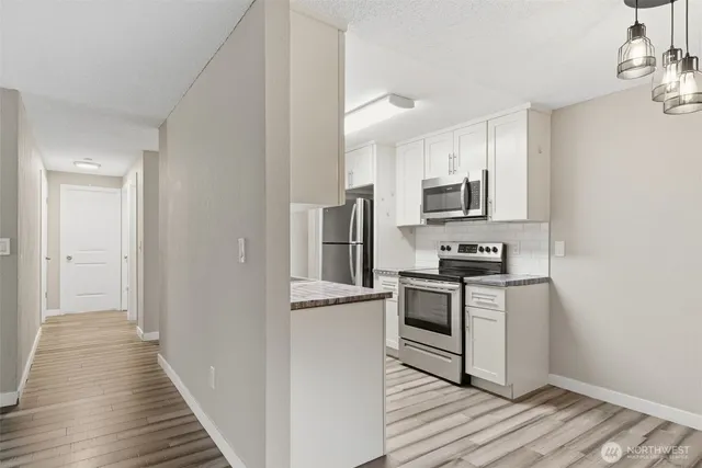 a kitchen with cabinets stainless steel appliances and wooden floor