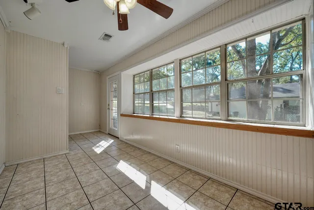 an empty room with windows and fan