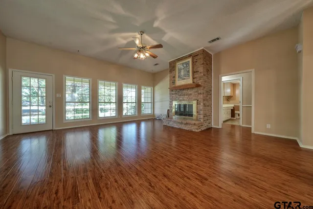 a view of an empty room with wooden floor and a window