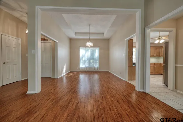 a view of an empty room with window and wooden floor