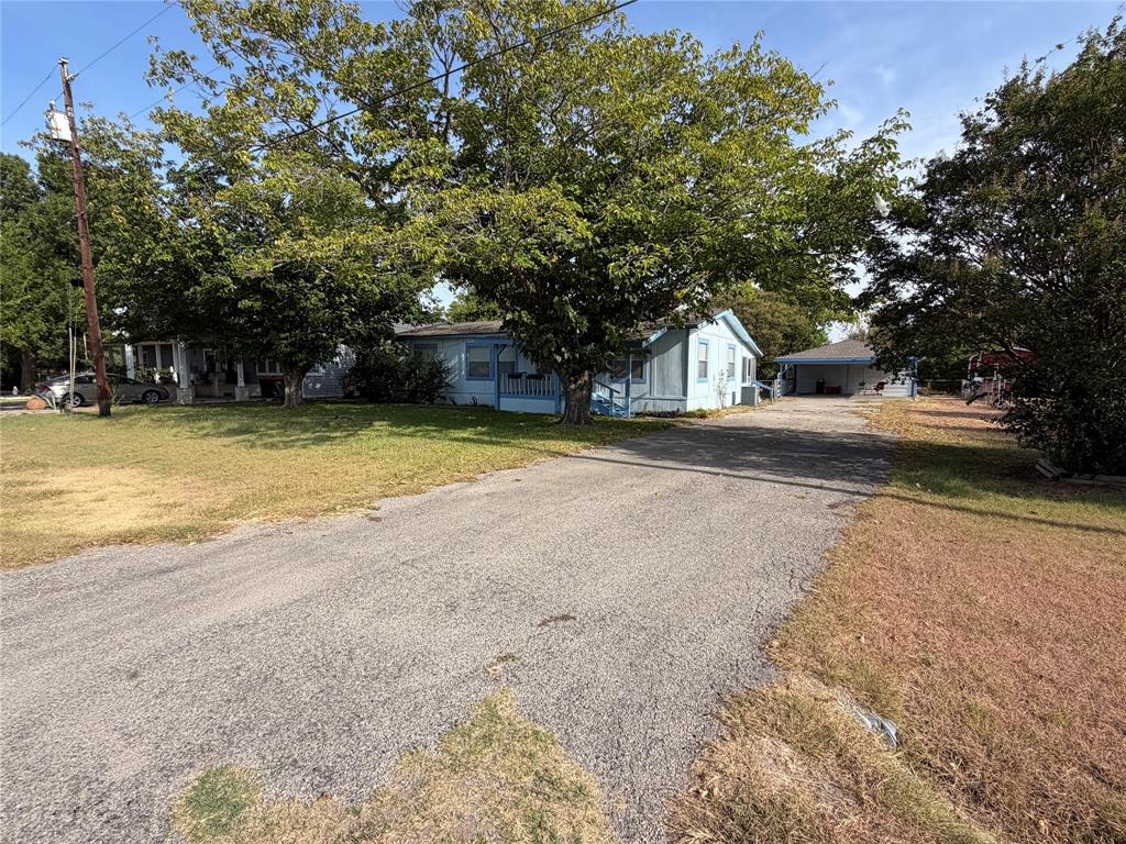 804 Preston Road Red Oak, TX 75154 - Photo 3 of 36 Gravel driveway leading to a blue exterior home with a covered front porch and mature trees