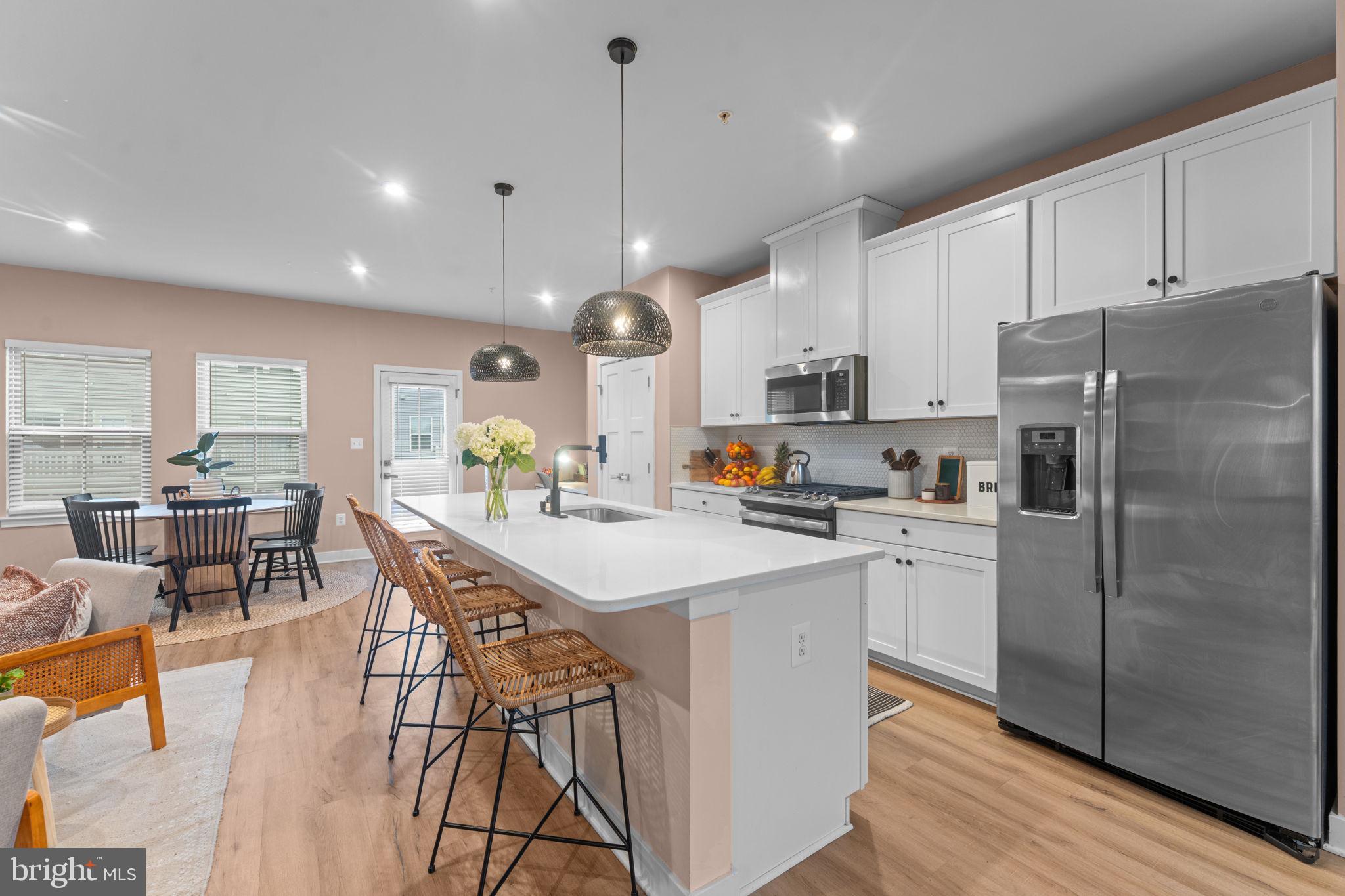 160 Lyons Creek Drive Laurel, MD 20708 - Photo 27 of 88 a kitchen with stainless steel appliances a refrigerator a stove a sink a dining table and chairs with wooden floor