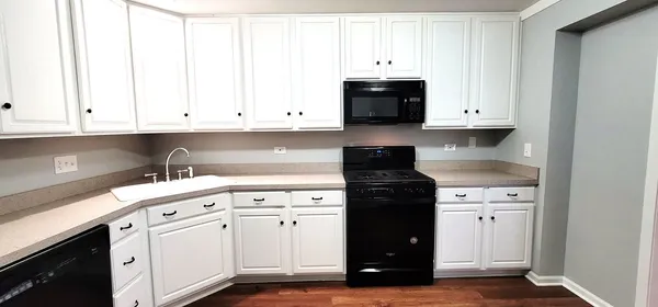 a kitchen with white cabinets and black appliances
