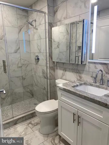 a bathroom with a granite countertop sink a toilet and shower