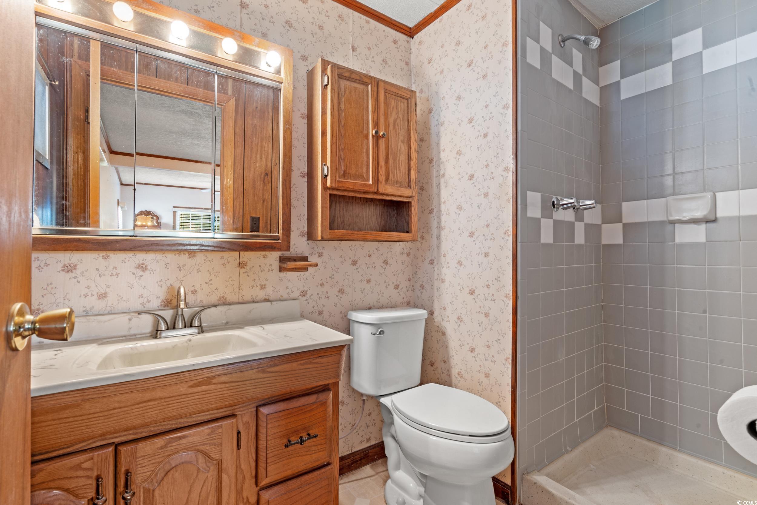 4422 Grady Road Mullins, SC 29574 - Photo 11 of 28 Bathroom featuring wallpapered walls, a stall shower, vanity, and ornamental molding
