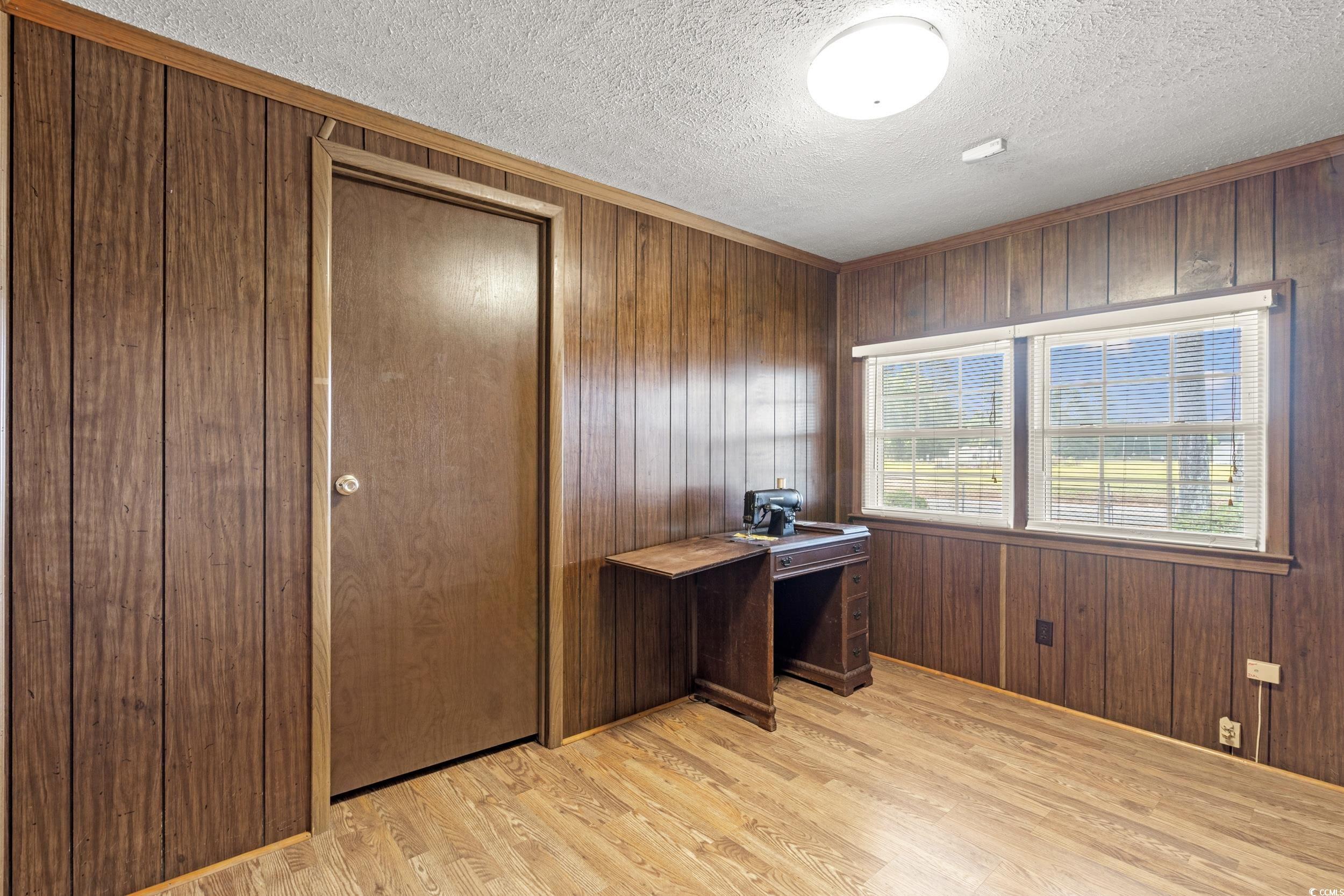 4422 Grady Road Mullins, SC 29574 - Photo 12 of 28 Home office with wooden walls, light wood-style flooring, and a textured ceiling