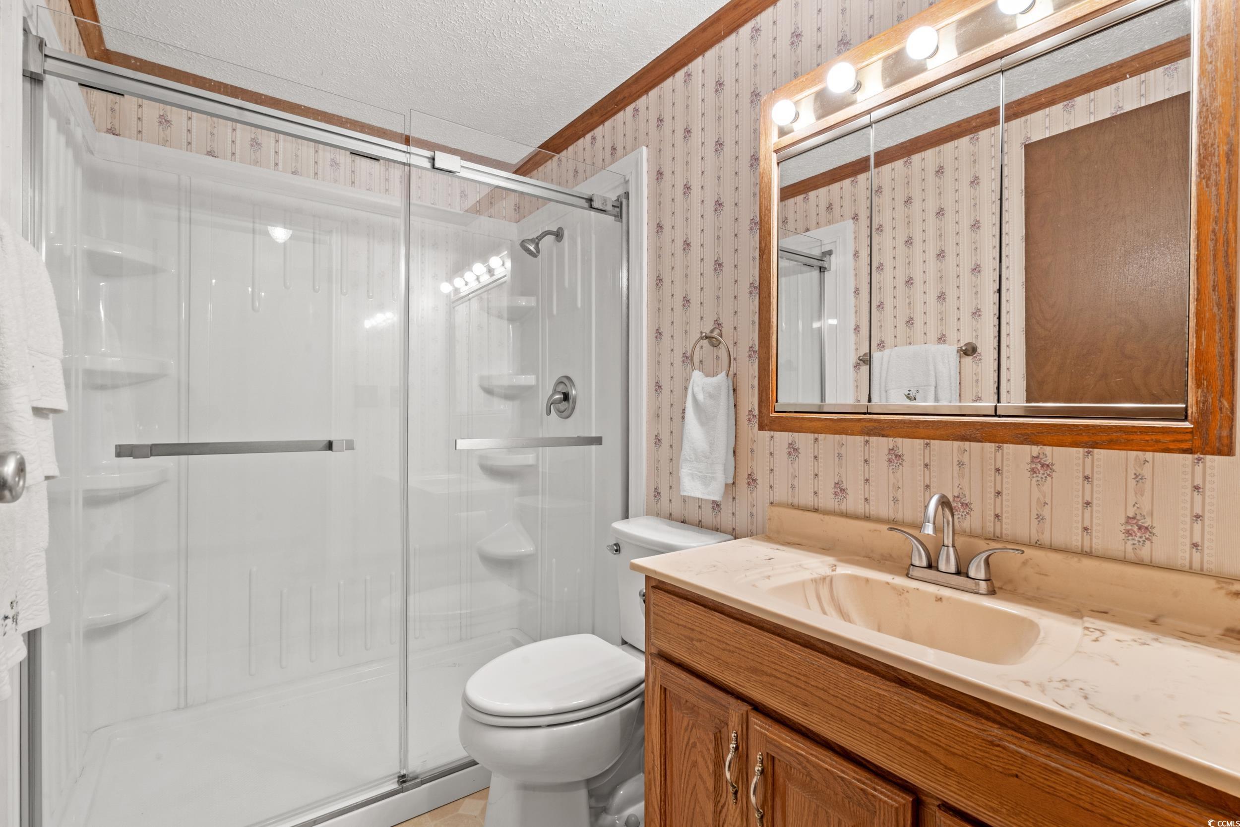 4422 Grady Road Mullins, SC 29574 - Photo 13 of 28 Full bathroom with a textured ceiling, wallpapered walls, a stall shower, vanity, and crown molding