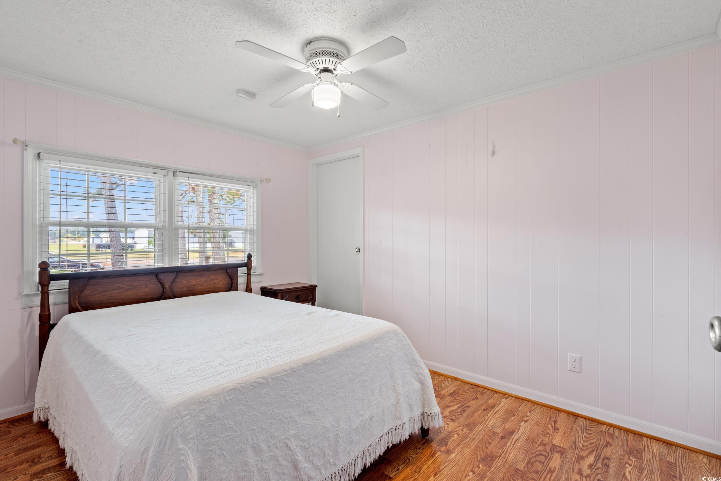 4422 Grady Road Mullins, SC 29574 - Photo 14 of 28 Bedroom featuring wood finished floors, ornamental molding, a textured ceiling, a ceiling fan, and wooden walls