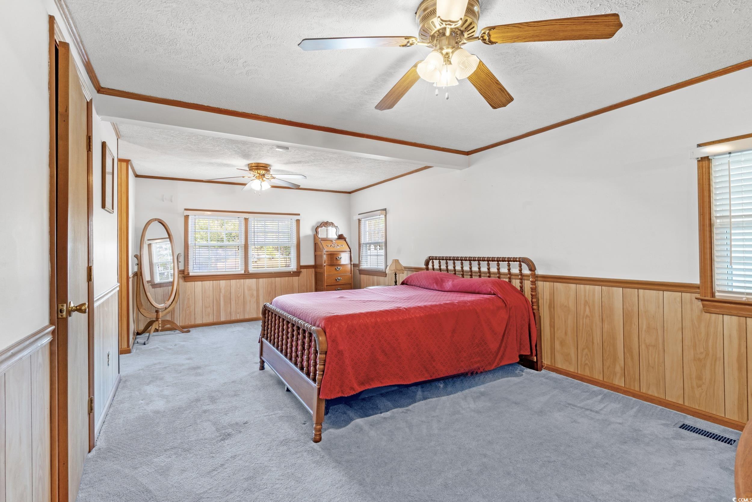 4422 Grady Road Mullins, SC 29574 - Photo 8 of 28 Bedroom with a textured ceiling, multiple windows, wooden walls, wainscoting, and carpet flooring