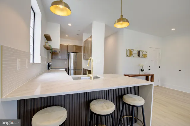 a kitchen with stainless steel appliances a table chairs and microwave