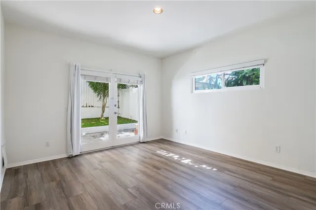 an empty room with wooden floor chandelier and windows