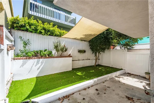 a view of a backyard with large trees and a wooden fence