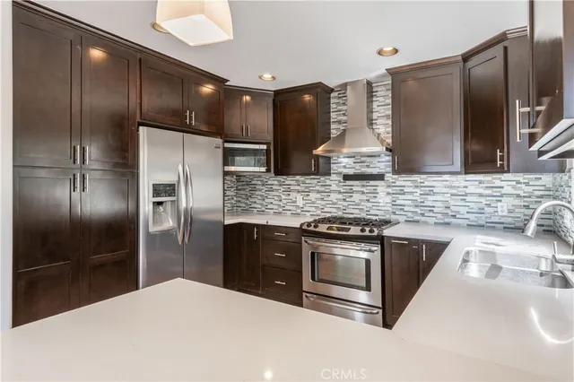 a kitchen with stainless steel appliances granite countertop a refrigerator a sink and a stove