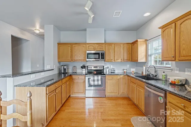 a kitchen with stainless steel appliances granite countertop a stove sink microwave and window