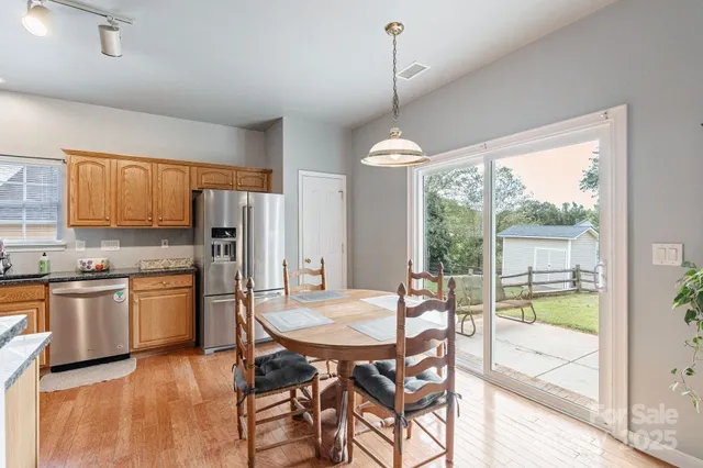 a kitchen with stainless steel appliances granite countertop a stove a refrigerator a kitchen island a table and chairs in it