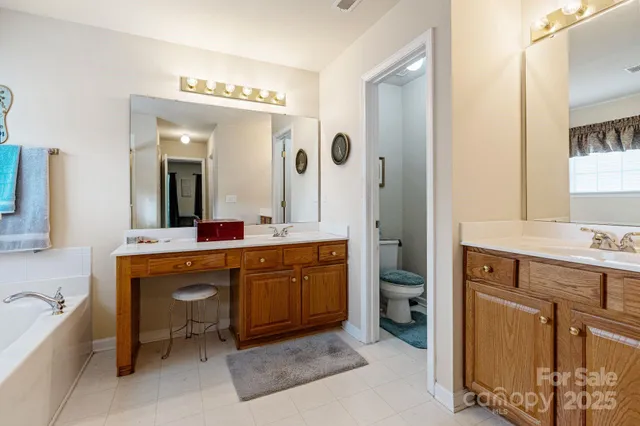 a spacious bathroom with a double vanity sink a large mirror and a bathtub