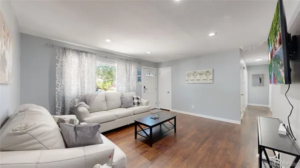 a living room with furniture and a wooden floor