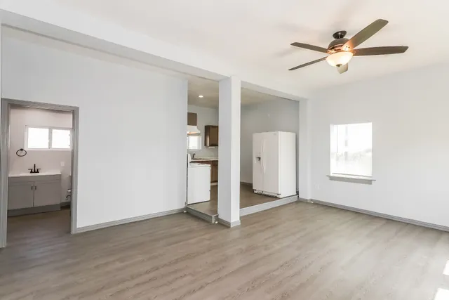 an empty room with wooden floor and a ceiling fan