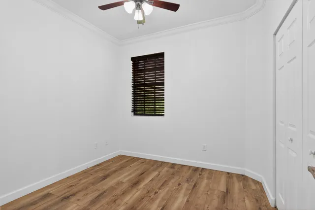 a view of empty room with wooden floor and ceiling fan