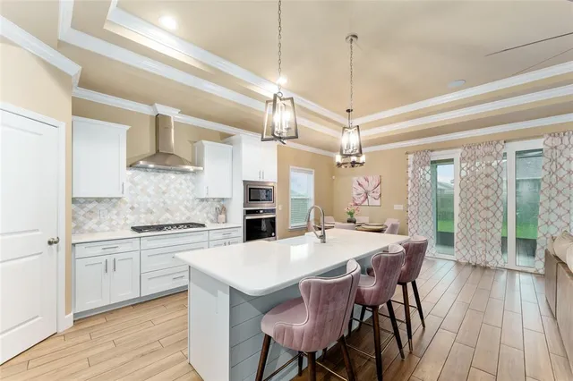 a kitchen with stainless steel appliances kitchen island granite countertop a dining table chairs and a refrigerator