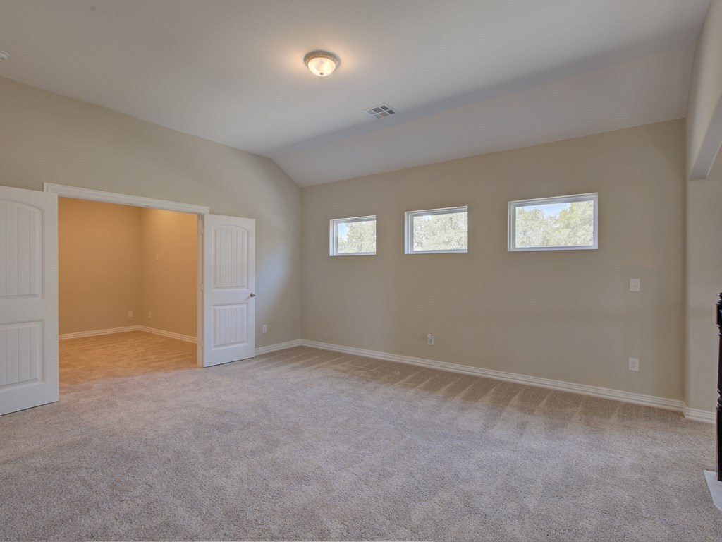 4303 Logan Ridge Drive Cedar Park, TX 78613 - Photo 20 of 24 Spacious room featuring vaulted ceilings, neutral-toned carpeting, and a trio of horizontal windows