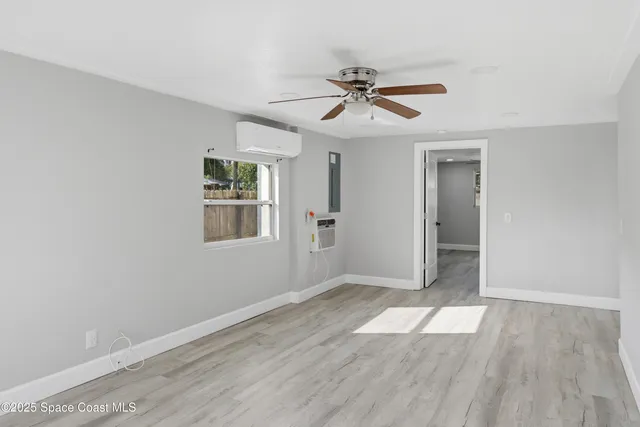 a view of empty room with wooden floor and fan