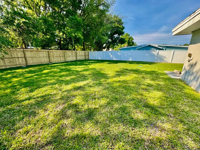 a view of yard with swimming pool and trees in the background