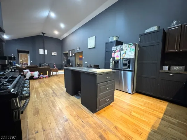 a kitchen with stainless steel appliances granite countertop a refrigerator a stove and a wooden floors